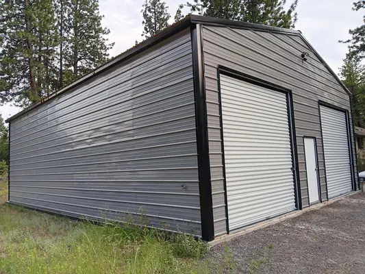 Enclosed metal garage with two roll-up doors and walk-in door