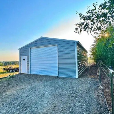Blue enclosed garage on a gravel pad