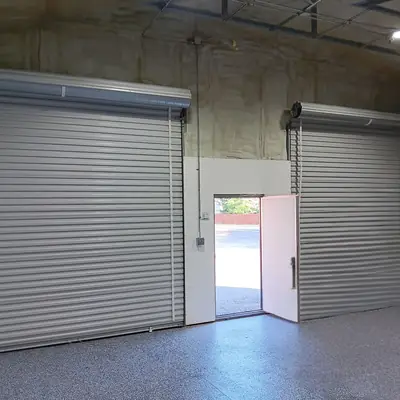 Insulated shop interior with two roll-up doors and a walk-in door